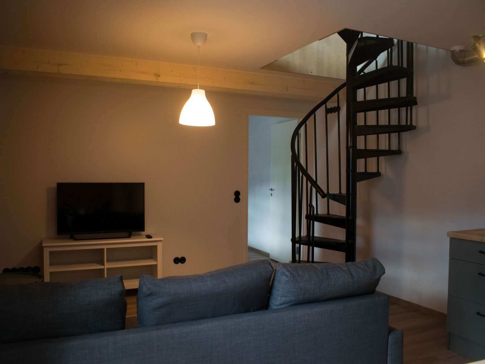 Diivan ja televiisor, kõrval trepp mis viib üles korrusele