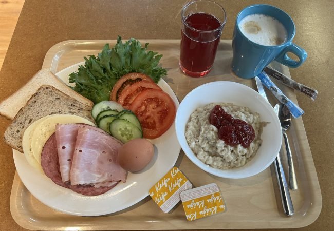 Hommikusöögi kandik, millel on puder moosiga, võileiva materjal, morss ning kohv.