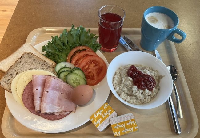 Hommikusöögi kandik, millel on puder moosiga, võileiva materjal, morss ning kohv.