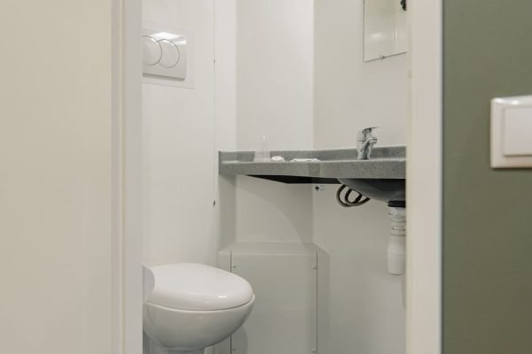 Vaade vannitoa uksest sisse, kus on näha WC pott ja valamu